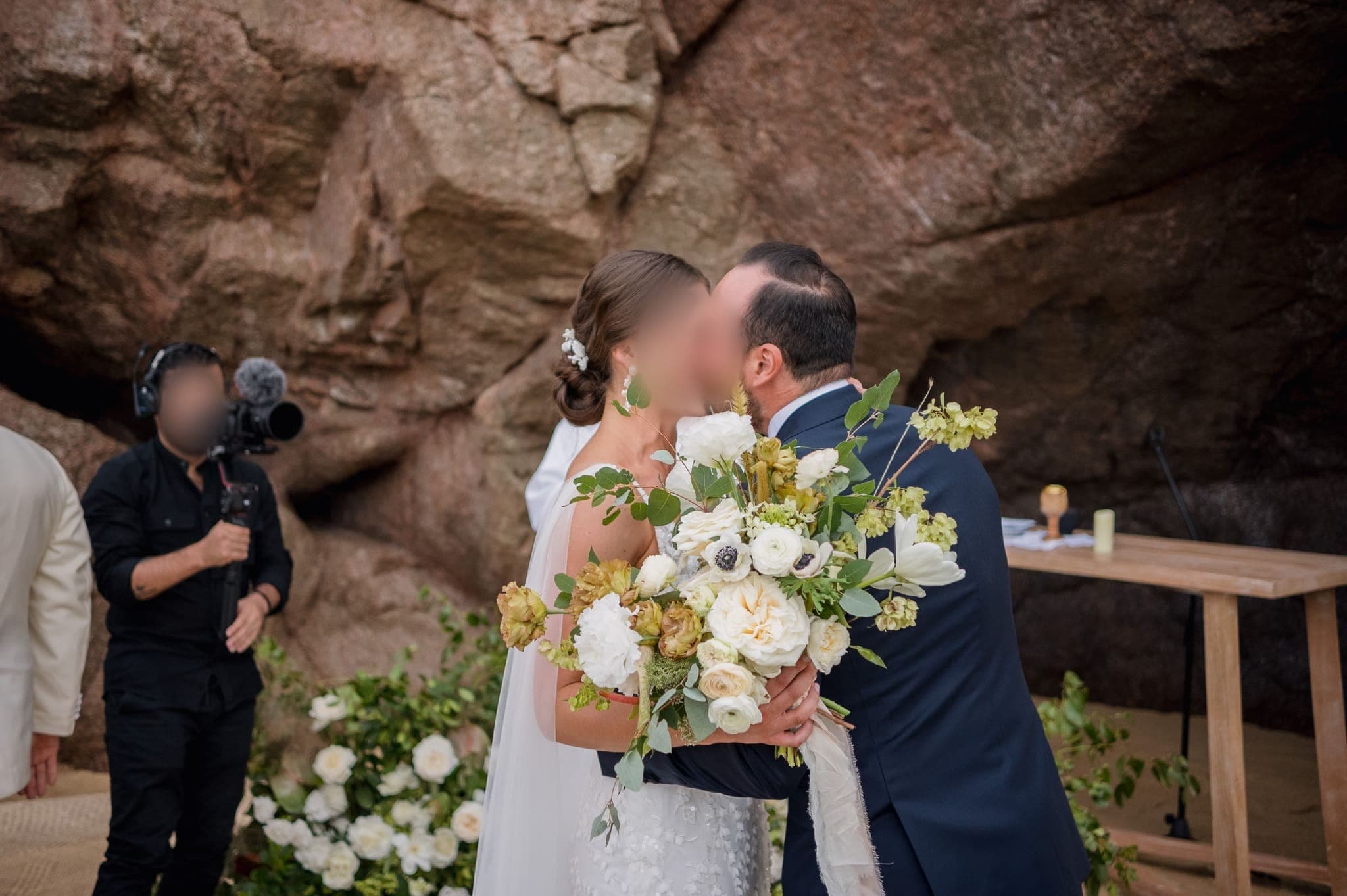 Primer beso de los novios en el altar entre rocas y ramos de flores