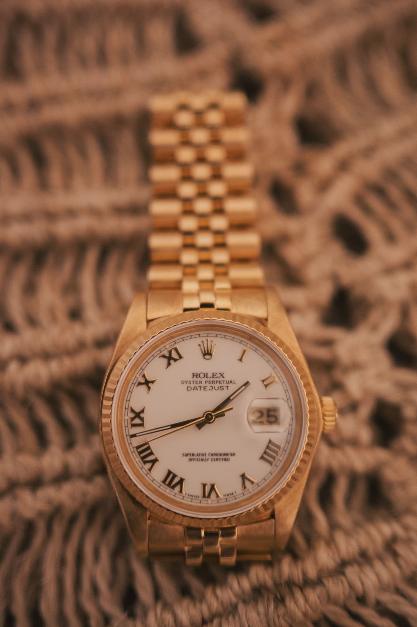 Reloj dorado del novio sobre textura tejida, detalle de boda