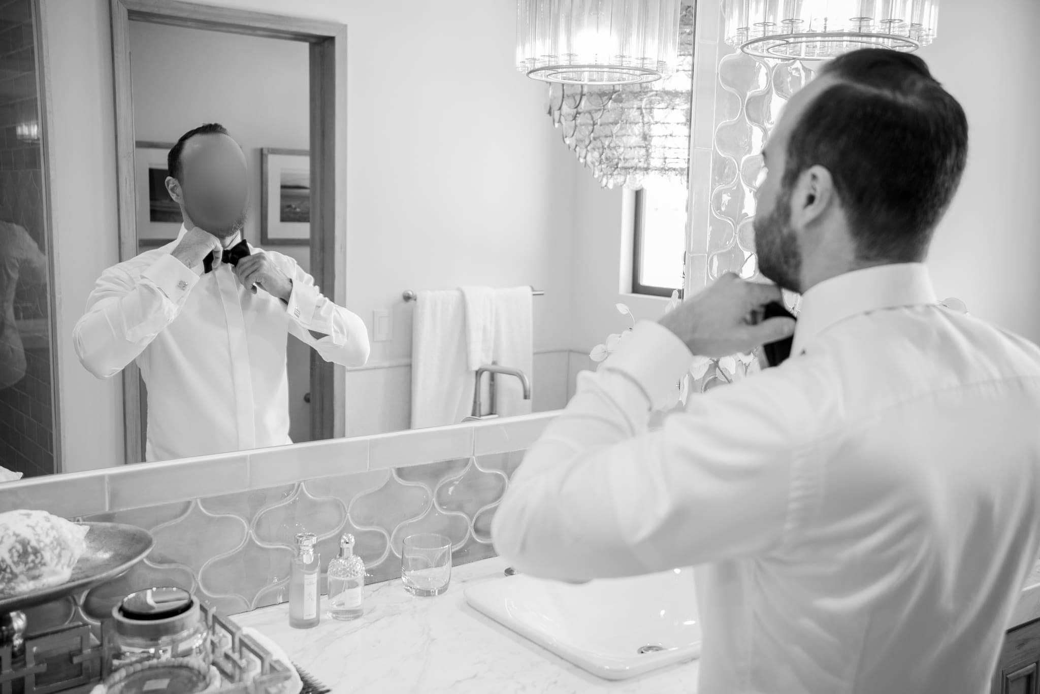 Novio ajustando su corbata frente al espejo, blanco y negro