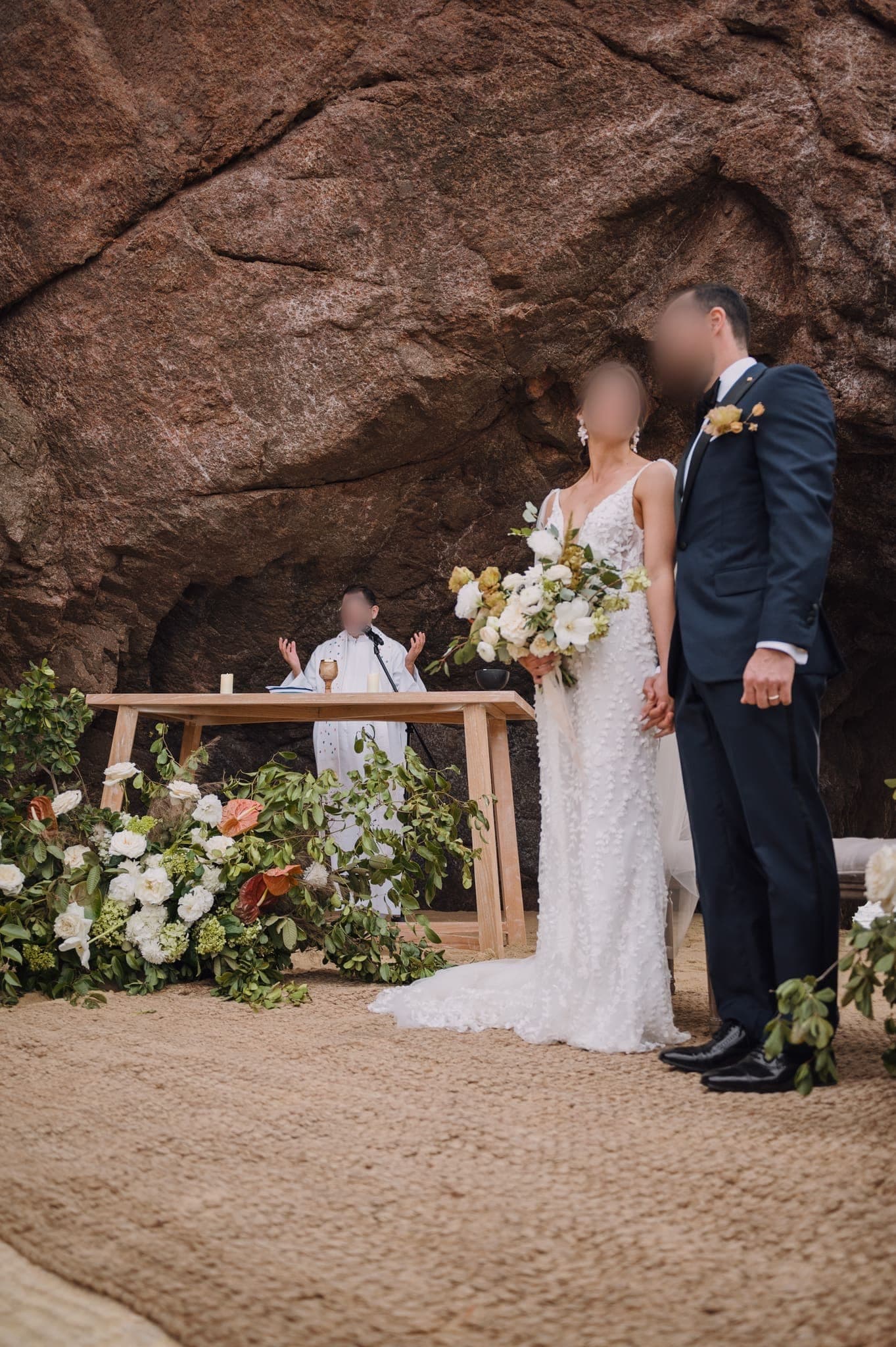 Los novios de pie en el altar entre arreglos florales