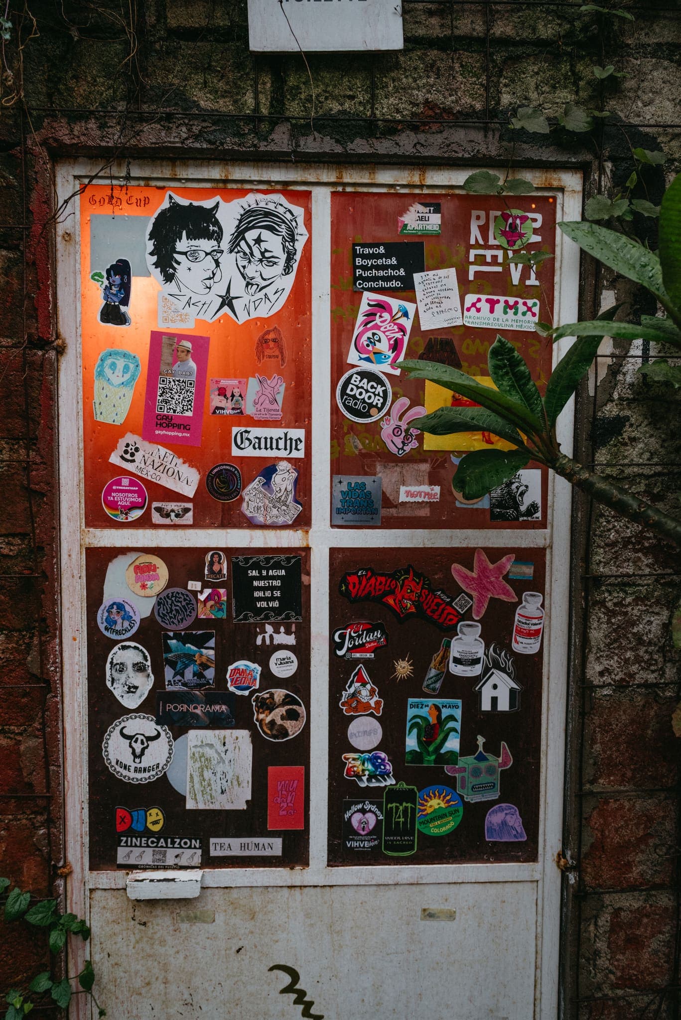 Puerta metálica cubierta de stickers y arte urbano