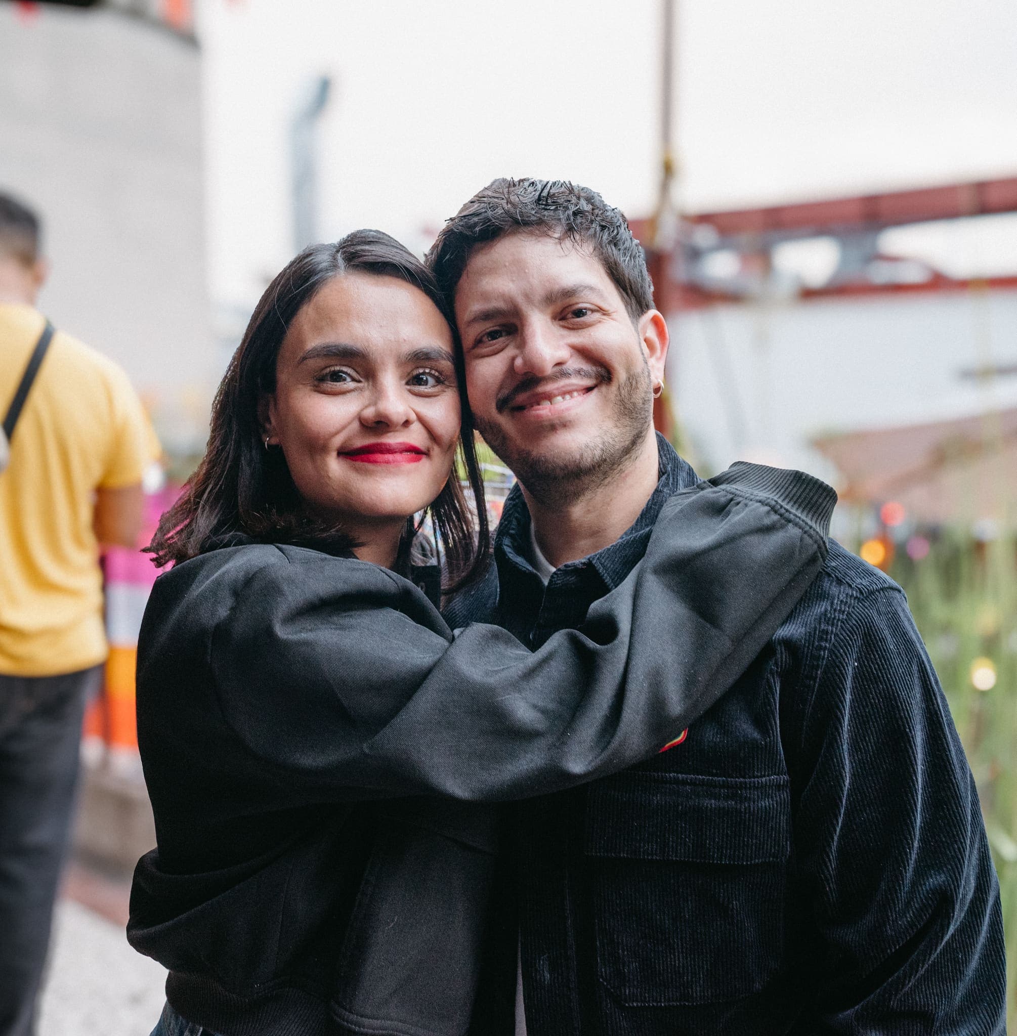 Pareja abrazada sonriendo en evento al aire libre