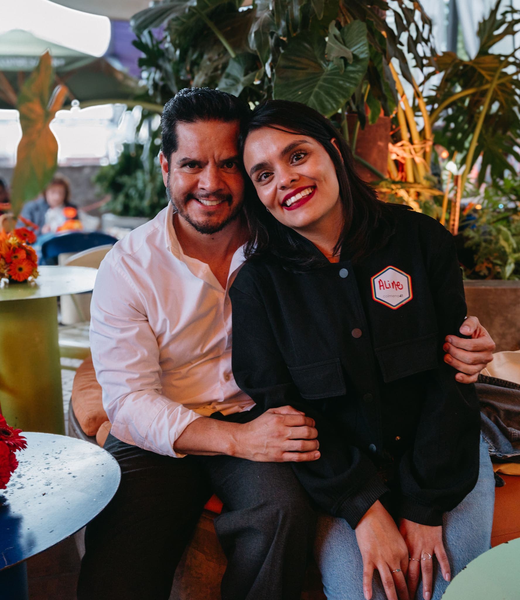 Pareja sentada sonriendo entre las plantas del patio