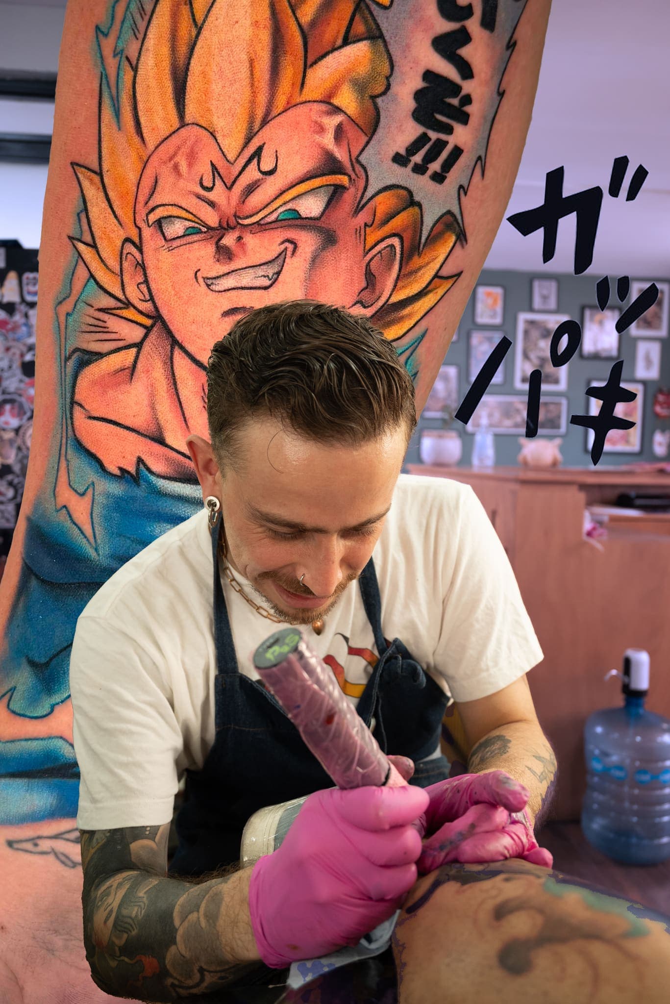 Tatuador trabajando frente a un mural de Dragon Ball