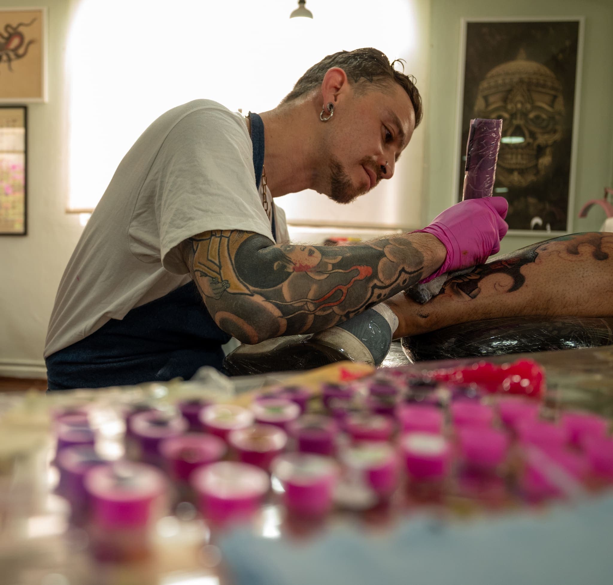 Tatuador concentrado con tintas rosas en primer plano