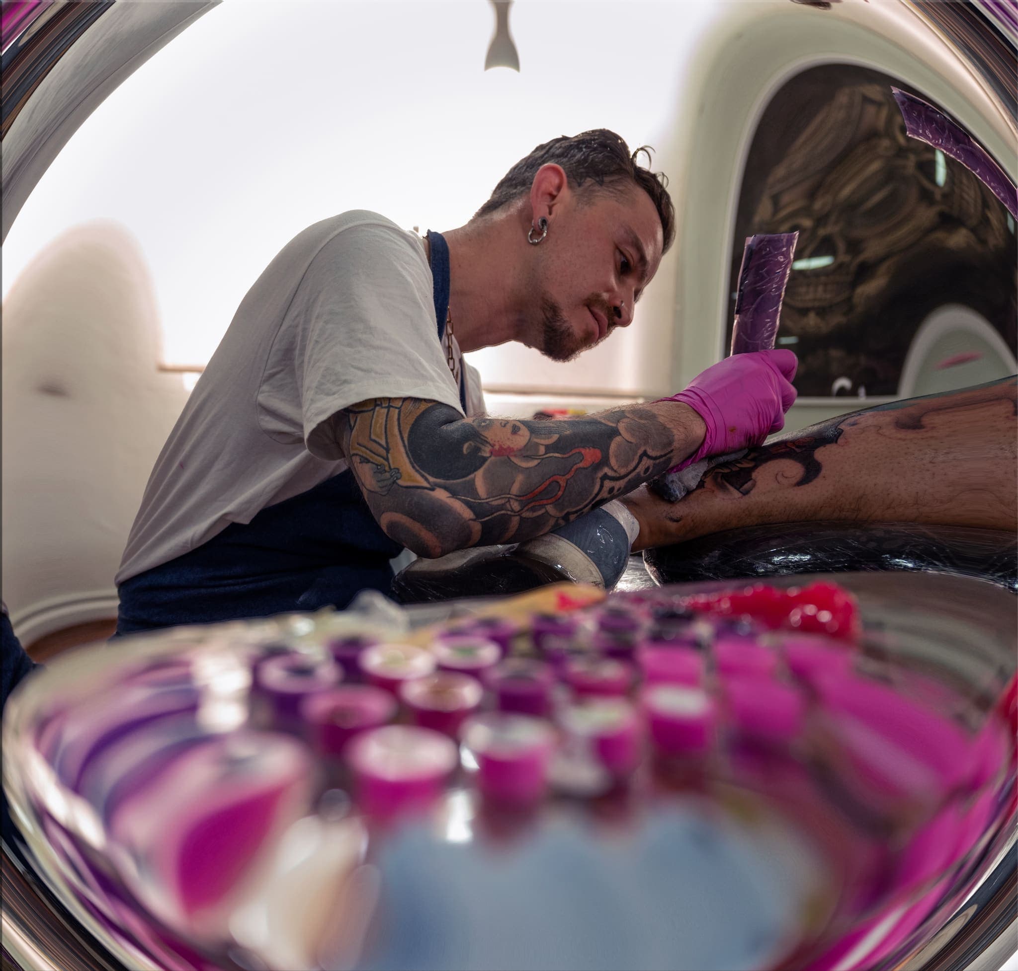 Reflejo de tatuador trabajando en espejo convexo