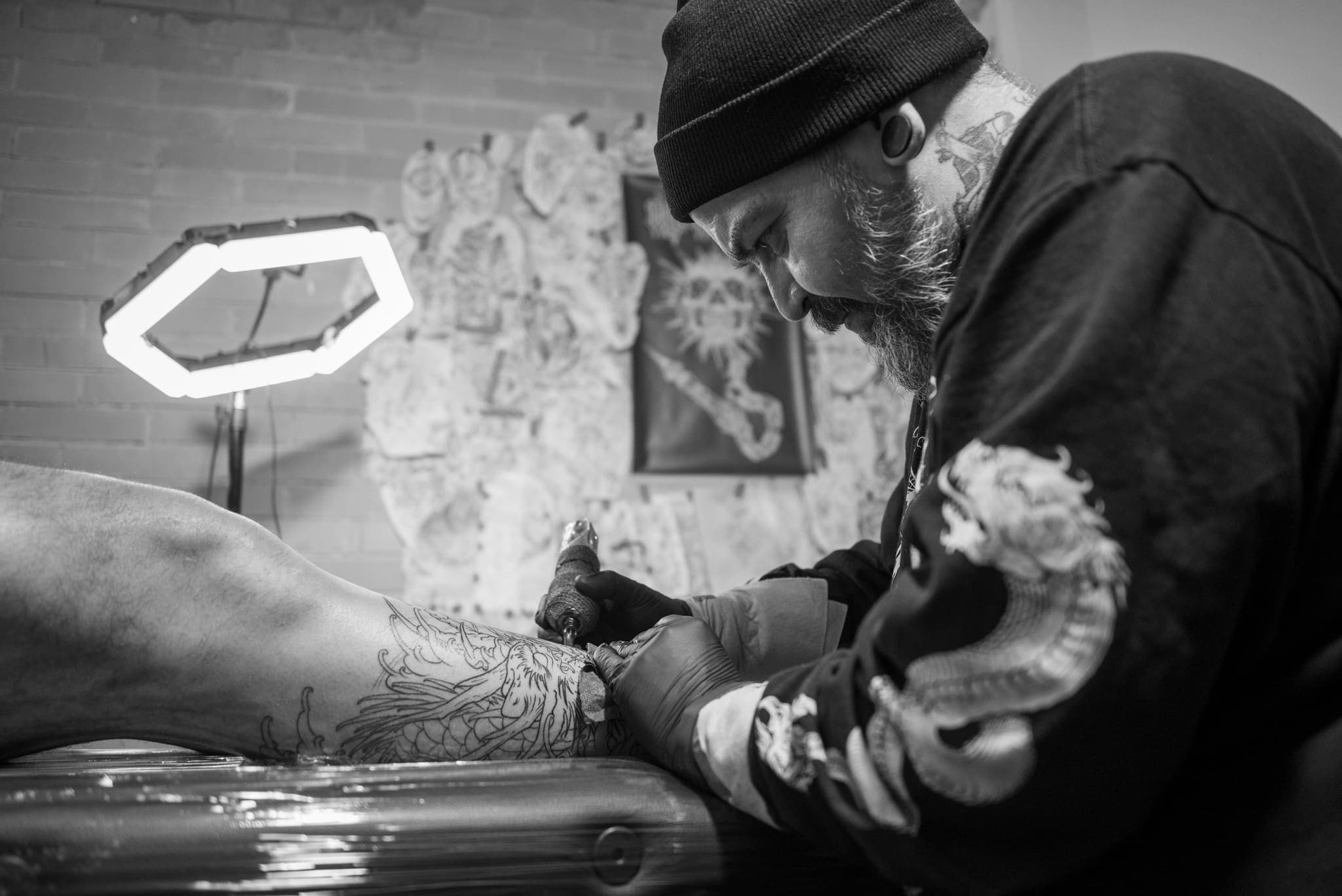 Tatuador con aro de luz trabajando, blanco y negro cenital
