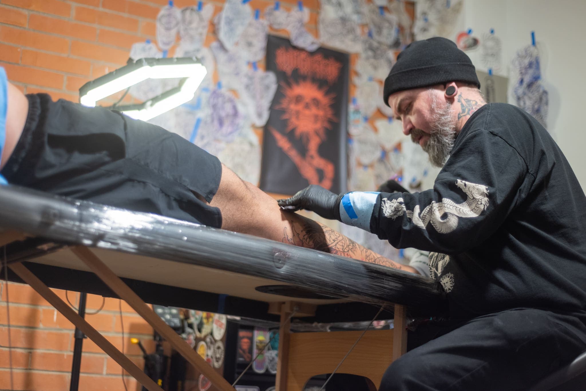 Tatuador con gorro trabajando bajo aro de luz hexagonal