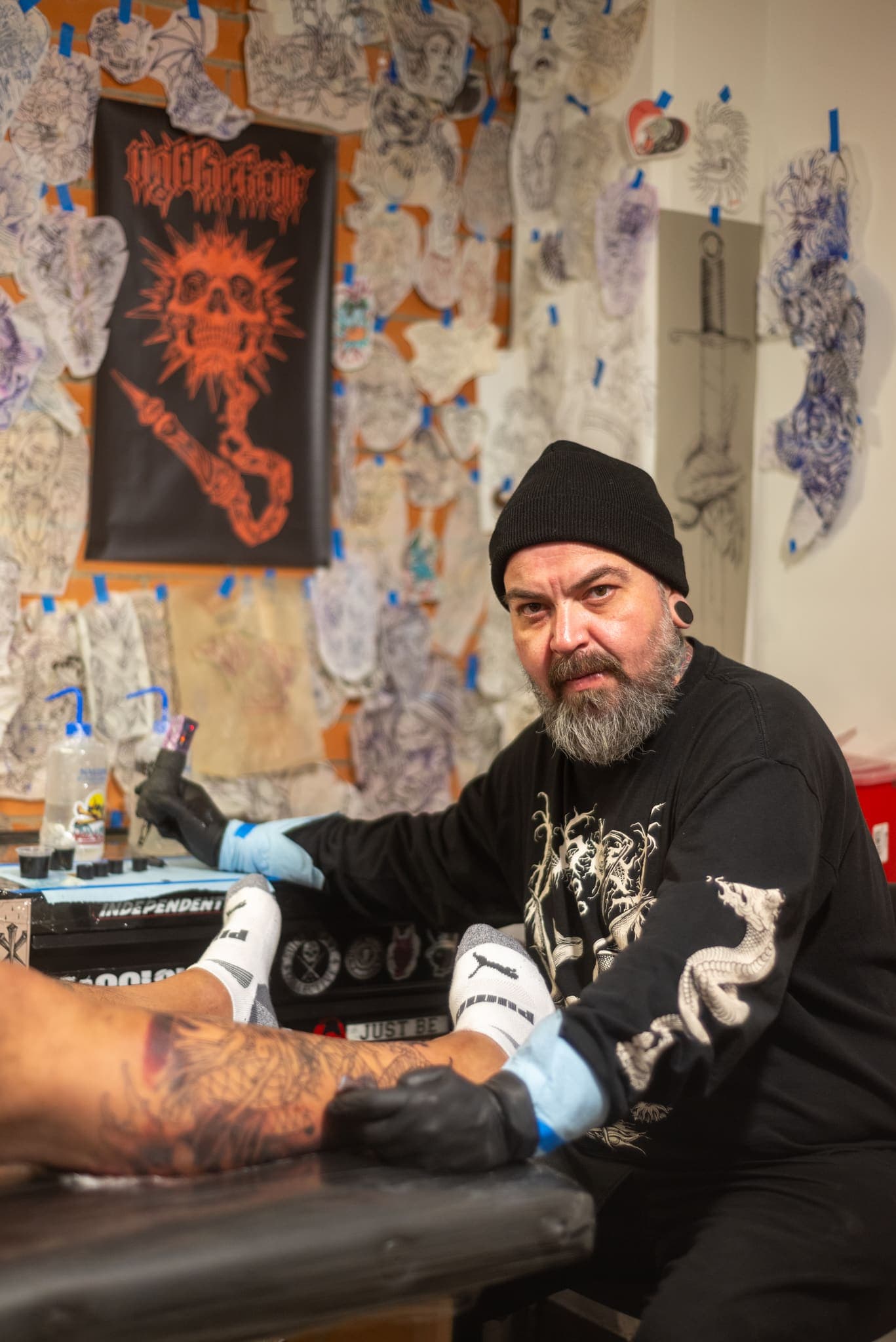 Retrato de tatuador en su estudio entre pósters y diseños