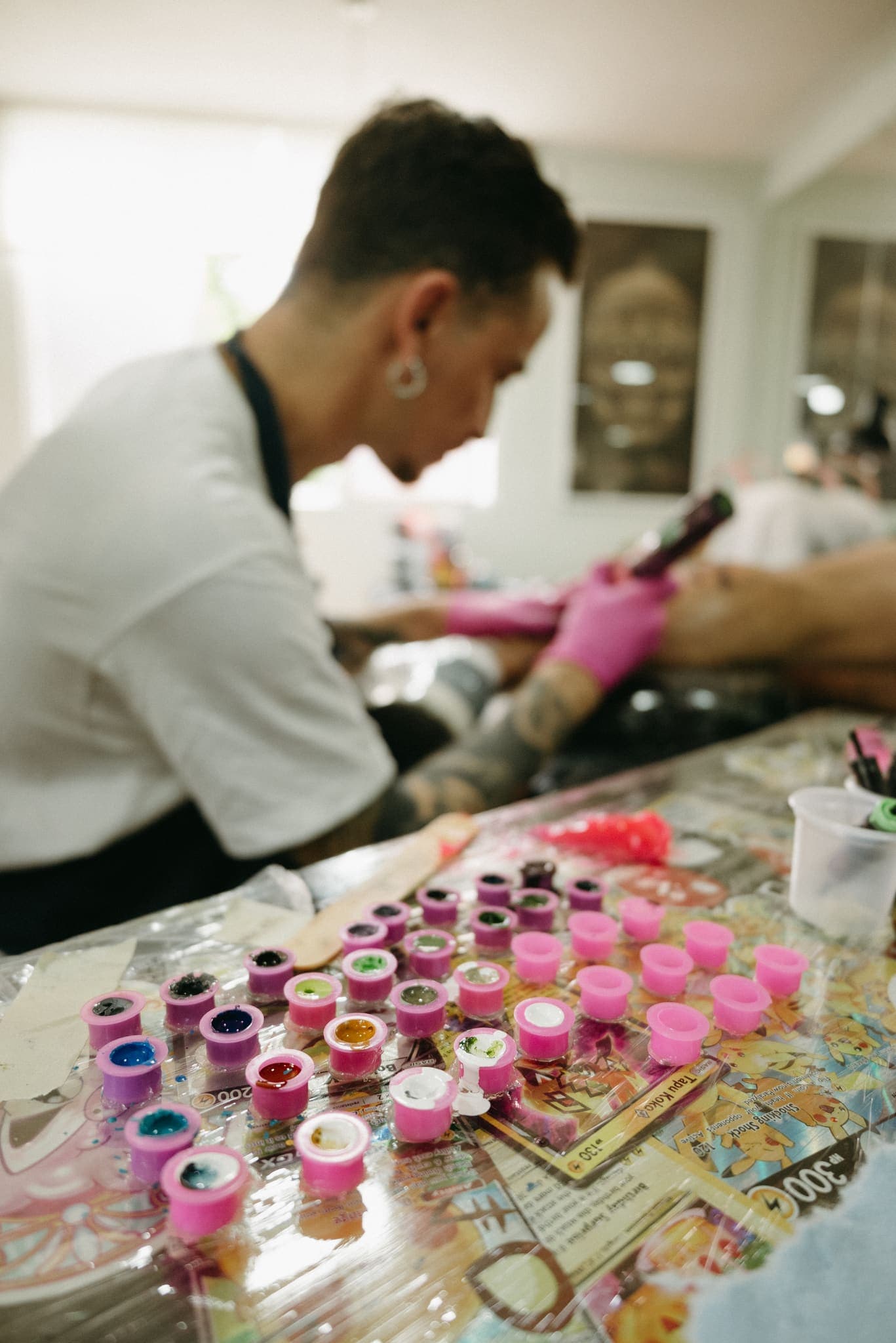 Tatuador de espaldas trabajando con su mesa de tintas de colores