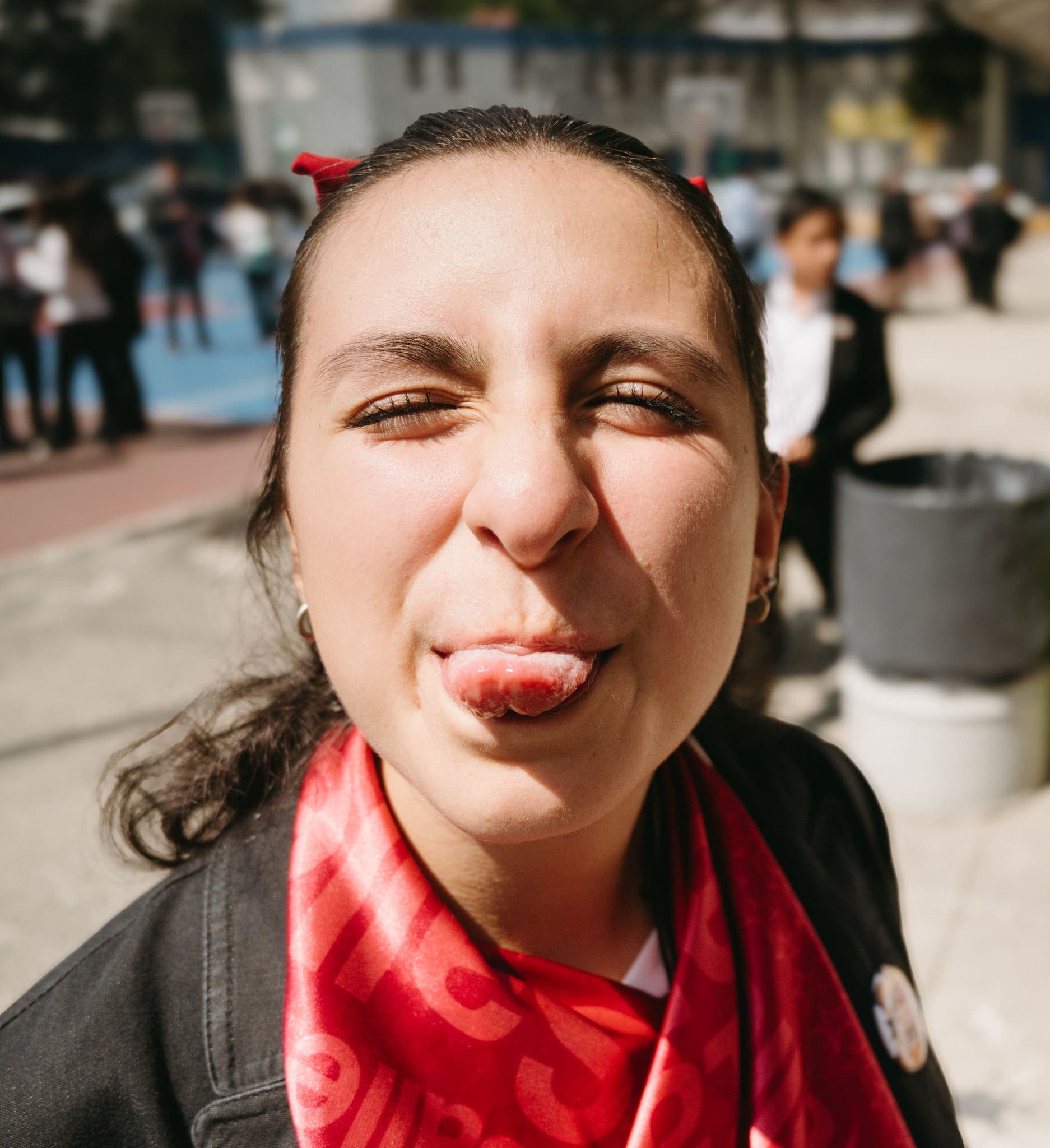 Retrato juguetón sacando la lengua con moño rojo en el cabello