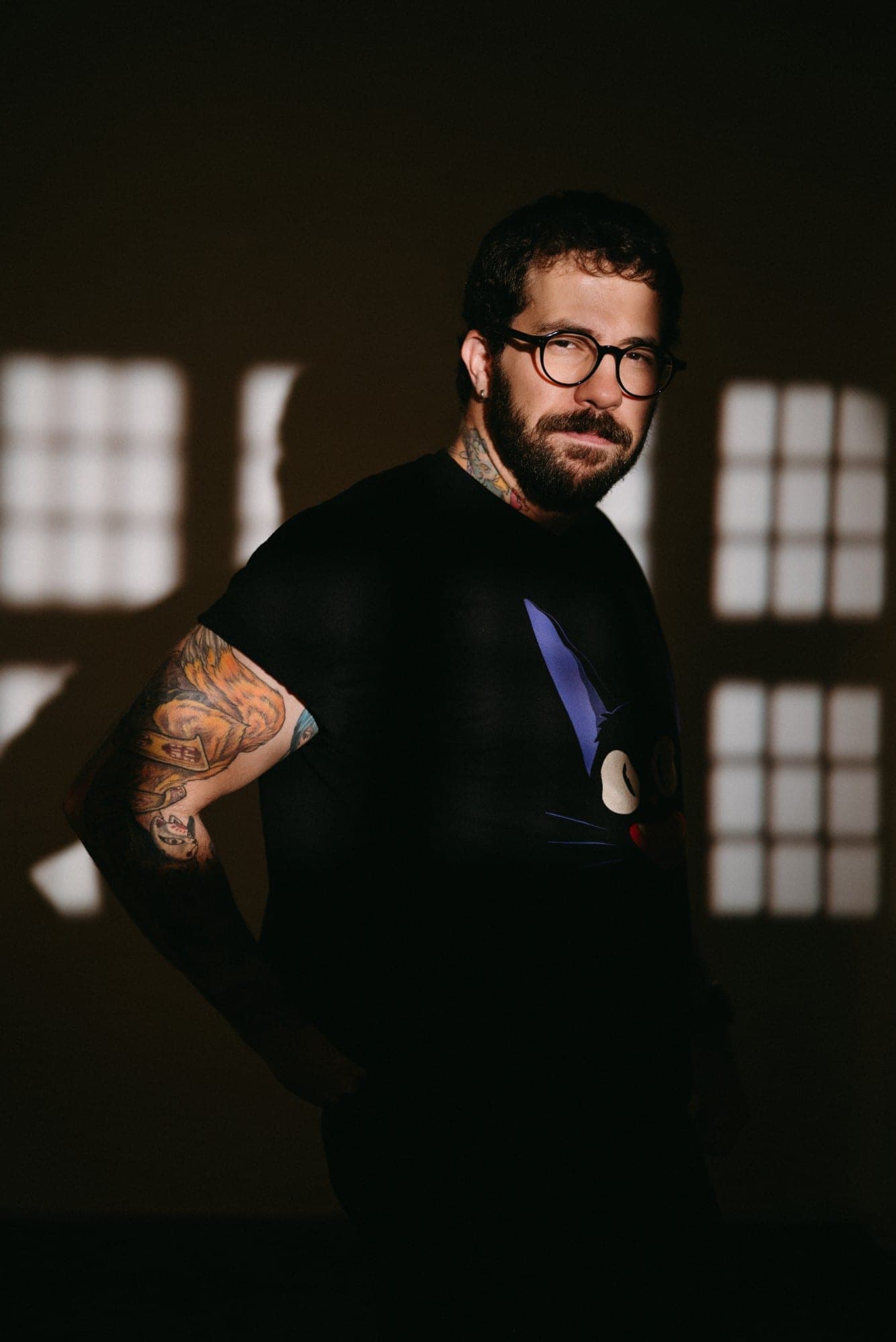 Andrés (Drux), fotógrafo, de pie con la luz de una ventana proyectada en la pared